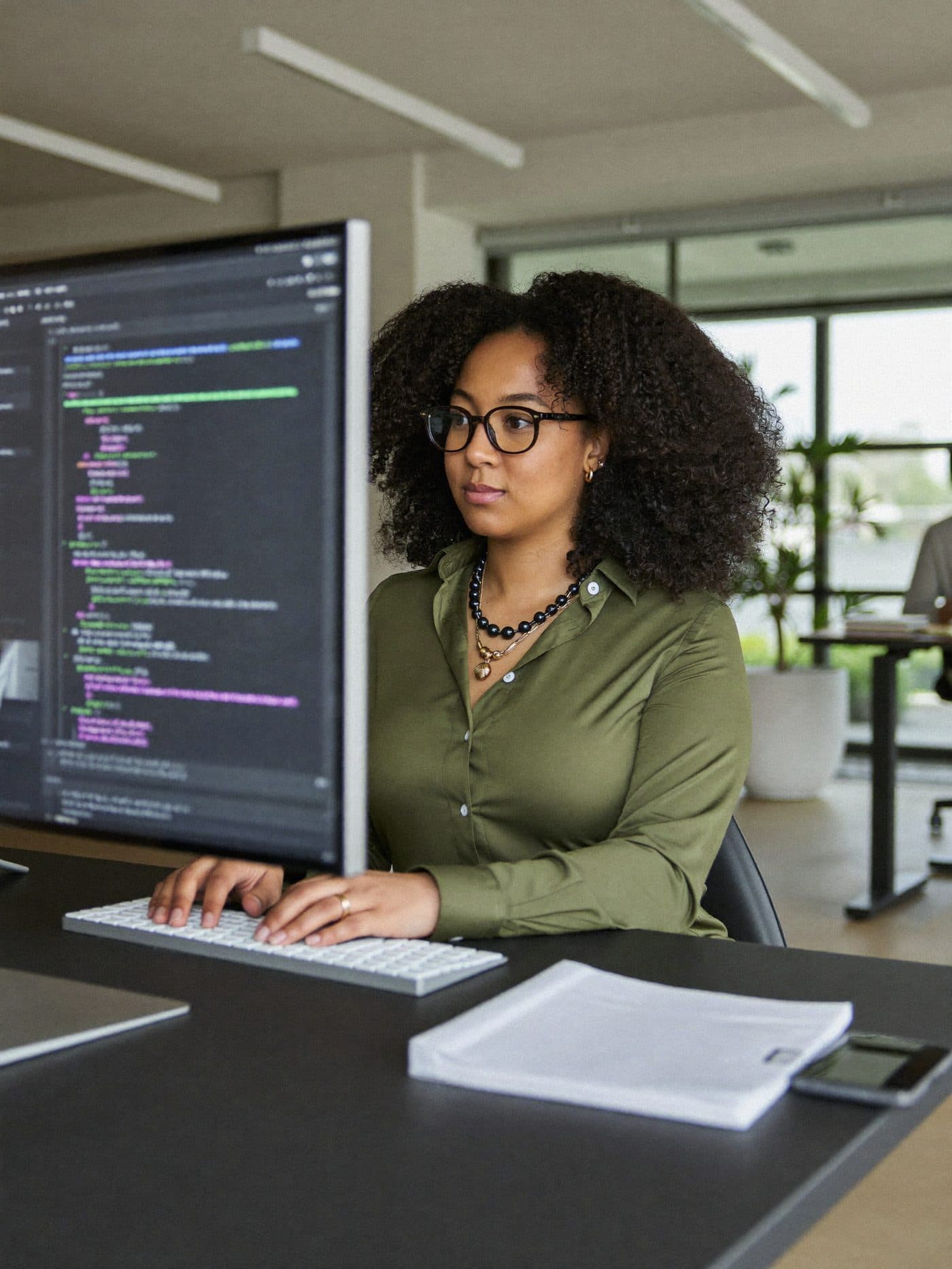 Software engineer working at a desk with two monitors showing code