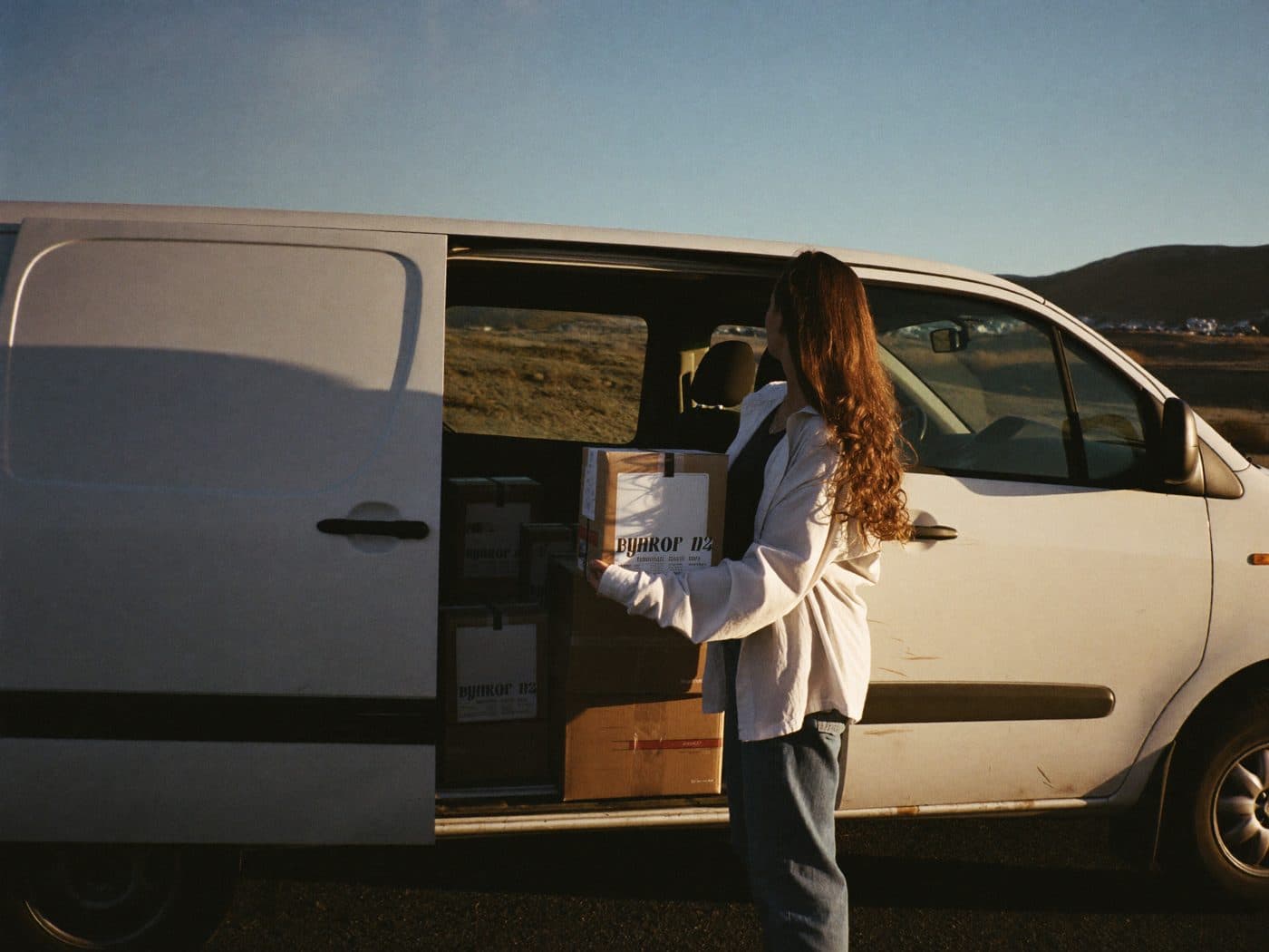 Delivery driver loading parcels into a van at dawn