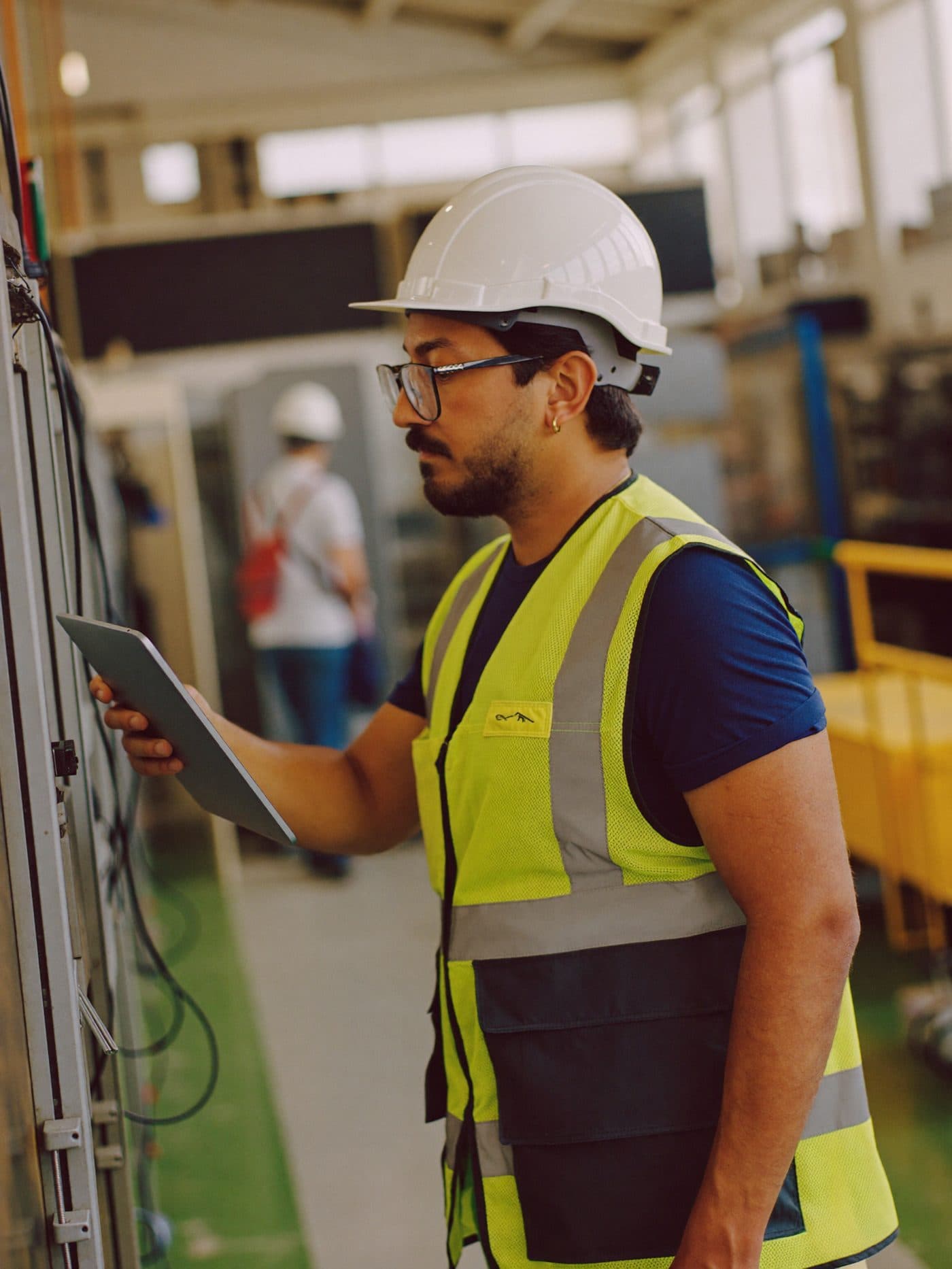 Shift supervisor holding a tablet while checking output on a busy production line